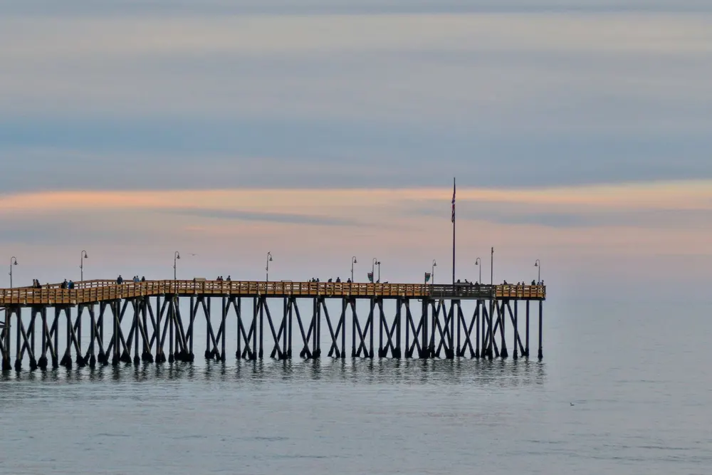 Ventura Pier stretching into calm ocean water at dusk